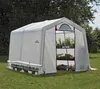 A white greenhouse with plants inside, set up on a grassy lawn. Voir les images du produit