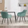 Two turquoise dining chairs with black legs are placed around a white dining table in a well-lit room. Produktbild-Vorschau