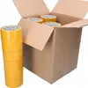 A cardboard box with several rolls of yellow double-sided tape inside and a stack of tape rolls to the left. Produktbild-Vorschau