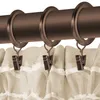 Close-up of curtain rings and clips attached to a curtain rod, with the top of a beige curtain visible. Produktbild-Vorschau