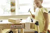 A young girl is using a workbench to hammer a nail into a piece of wood. Produktbild-Vorschau