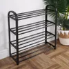 A black metal shoe rack with four shelves is shown against a white wall and on a wooden floor. A potted plant is visible to the right. Anteprima dell’immagine prodotto