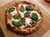 A pizza is placed on a wooden cutting board. Podgląd zdjęcia produktu