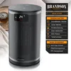A cylindrical heater is shown in front of a blurred background with some fabric and a tray. Produktbild-Vorschau