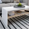 A close-up view of a modern white coffee table with a wooden shelf, placed on a striped rug in a living room setting. Anteprima dell’immagine prodotto