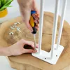 A person is screwing a white hairpin leg onto a wooden surface. Produktbild-Vorschau