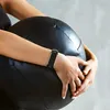 A person wearing a fitness tracker is holding a large black exercise ball. Voir les images du produit