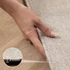 A hand is pressing down on a carpet, showing its thickness. Náhled obrázku produktu