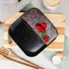 A slice of chocolate cake with raspberries and powdered sugar on a baking pan, placed on a wooden board with kitchen utensils and an eggshell nearby. Náhľad obrázku produktu