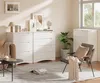 A modern living room or bedroom scene featuring white dressers, a chair, and decorative items. Anteprima dell’immagine prodotto