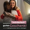 Two women hugging, one is holding a gift. Produktbild-Vorschau