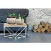 A modern living room scene with a sofa, coffee table with plants, and a pile of firewood. Anteprima dell’immagine prodotto
