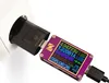 A black USB adapter plugged into a white wall socket, connected to a purple USB testing device displaying various electrical readings. Produktbild-Vorschau