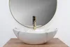 A close-up shot of a marble-patterned vessel sink with a gold faucet, placed on a wooden surface, with a round mirror in the background. Anteprima dell’immagine prodotto
