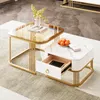 A set of two nesting coffee tables with gold metal frames and different tabletop finishes, one with a glass top and the other with a marble-look finish and a drawer. Náhľad obrázku produktu