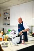 A chef is preparing food in a modern kitchen with a white multi-functional cooker. Podgląd zdjęcia produktu