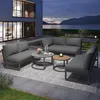 A modern outdoor living space at dusk, featuring a grey sectional sofa set with coffee tables, situated on a patio next to a body of water and a contemporary house. Produktbild-Vorschau