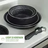 Cookware stacked inside a cabinet, with a detachable handle in the foreground. Voir les images du produit