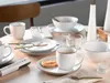 A table setting with a coffee cup, cookie, and tableware. Náhľad obrázku produktu