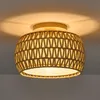 A close-up shot of a ceiling light fixture with a woven rattan shade. Produktbild-Vorschau