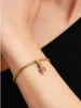 A close-up shot of a person's wrist wearing a gold bracelet with a charm. Anteprima dell’immagine prodotto