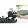 A hand holding a black cutlery holder with cutlery inside, above a black dish rack. Podgląd zdjęcia produktu