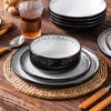 A table setting with a stack of plates and bowls, a glass of drink, and cutlery. Náhled obrázku produktu