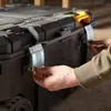 A person's hands are shown closing the latches on a black tool chest. Anteprima dell’immagine prodotto