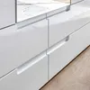 A close-up view of a white, high-gloss dresser with integrated handles, showing two drawers and a mirrored surface above. Produktbild-Vorschau