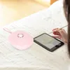 A person is using a tablet and stylus on a bed, with a pink electronic device next to it. Podgląd zdjęcia produktu