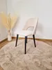A chair is placed on a round rug in front of a vase with dried flowers. Produktbild-Vorschau