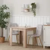 A dining set with a table and two chairs in a room with a plant and shelving. Voir les images du produit
