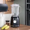 A black blender with a glass jug sits on a wooden countertop, with a bottle of milk, a jar of seeds, and bananas nearby. Produktbild-Vorschau