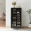 A shoe cabinet filled with shoes, placed in a room with a floor lamp and a sofa in the background. Produktbild-Vorschau