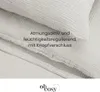 A close-up view of a light taupe musselin bed linen set, showing texture and button closure. Produktbild-Vorschau