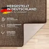 A close-up of a brown carpet with text overlays describing its features and origin. Produktbild-Vorschau