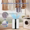 A dehumidifier is shown in a room with clothes drying on a rack, a washing machine, and plants. The image illustrates the product's function in drying clothes. Náhled obrázku produktu