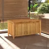 A bamboo storage chest sits on a tiled patio next to outdoor furniture, with blinds in the background. Produktbild-Vorschau