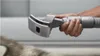 A hand holding a pet grooming attachment for a vacuum cleaner, positioned over a dog's fur. Podgląd zdjęcia produktu