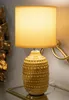 A table lamp with a textured base and a fabric shade sits on a glass shelf. Anteprima dell’immagine prodotto