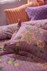 A close-up view of a bed with floral patterned pillows and bedding. Produktbild-Vorschau