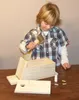 A young boy is assembling a wooden birdhouse kit on a table. Produktbild-Vorschau