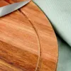 A close-up view of a wooden cutting board with a knife and a piece of fabric. Voir les images du produit