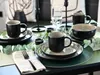 A table setting with mugs, plates, and a bowl, decorated with eucalyptus leaves. Produktbild-Vorschau