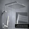 A modern chrome shower set with a square overhead shower and a handheld showerhead, mounted on a grey tiled wall. Produktbild-Vorschau