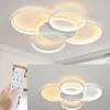 A modern white ceiling lamp with five interlocking rings, illuminated from within, mounted on a white ceiling. Voir les images du produit