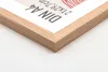 A close-up view of a wooden picture frame corner, showing the texture of the wood and a portion of the paper insert with text. Produktbild-Vorschau