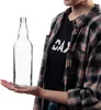A person is holding an empty glass bottle. Produktbild-Vorschau