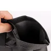 A hand is holding open a black fabric pouch with a velcro closure. Produktbild-Vorschau