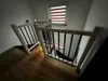 A wooden staircase with black railings and a window with blinds. Produktbild-Vorschau